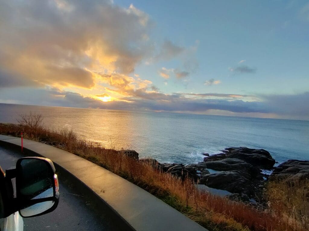 Lever de soleil sur la mer aux îles Lofoten en Norvège, observé depuis la route après une nuit de traversée en tempête lors d’un voyage en van.