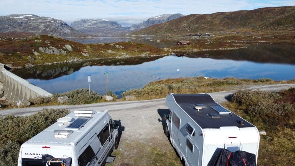 Deux vans aménagés stationnés face à un lac de montagne dans le Telemark en Norvège, rencontre entre familles en road trip, paysage automnal