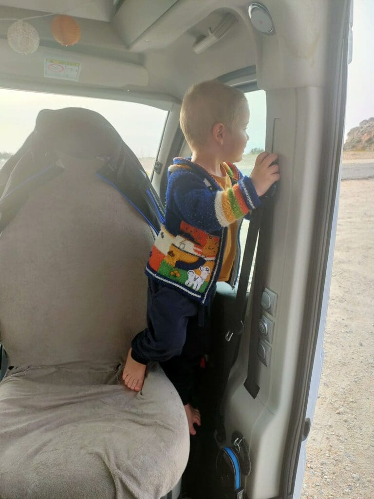 Enfant debout sur le siège avant d'un van lors d'une pause road trip en famille