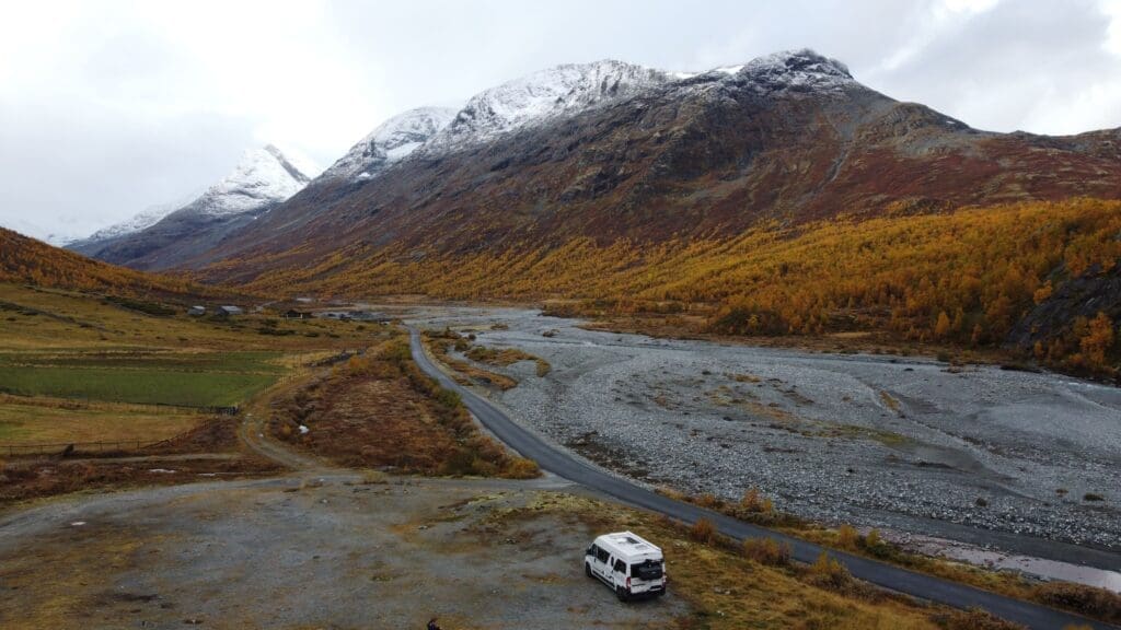 Road trip en van en Norvège à l'automne avec montagnes enneigées et forêt aux couleurs automnales