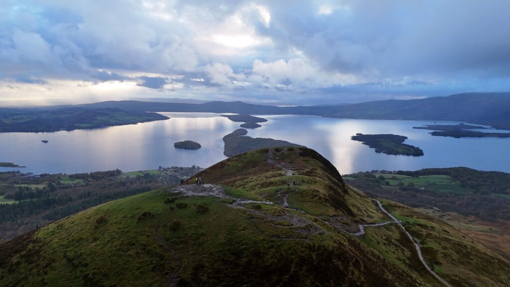 Vue aérienne depuis Conic Hill sur les collines verdoyantes, les nombreuses îles du Loch Lomond et un ciel nuageux en Écosse.