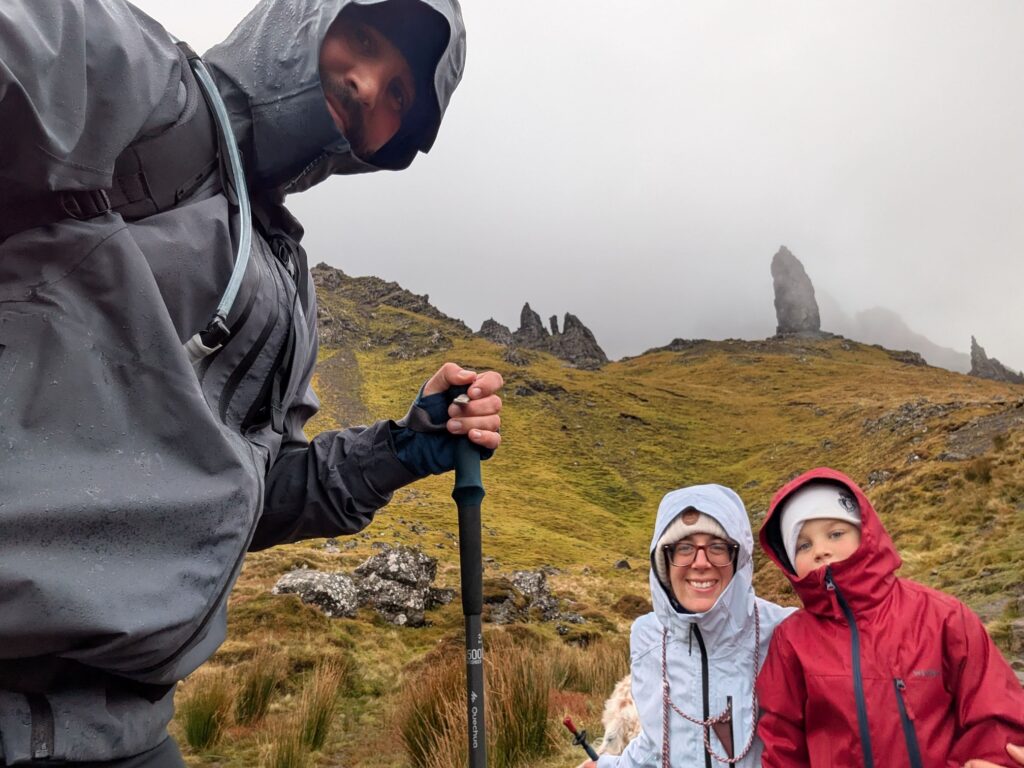 Famille en vêtements imperméables devant les aiguilles rocheuses de l'Old Man of Storr, partiellement enveloppées de brume sur l'île de Skye.