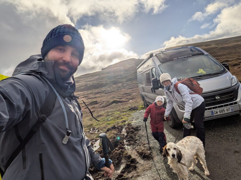 Famille avec un enfant et un setter anglais devant un van Adria, au départ d'une randonnée dans les paysages montagneux du Quiraing sur l'île de Skye.