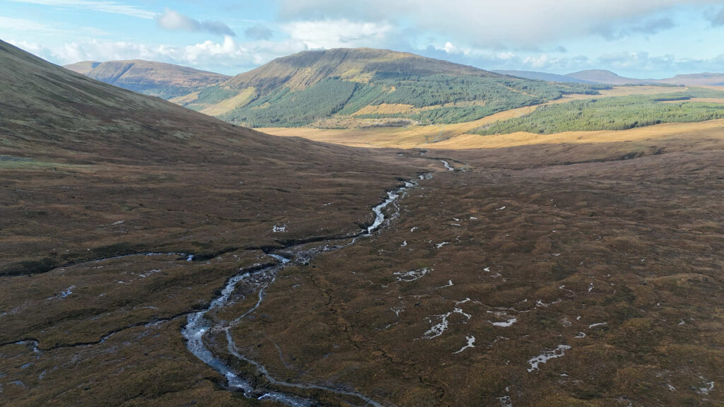 Vue aérienne d'une rivière traversant les landes automnales de Glen Brittle, avec des montagnes en arrière-plan, près des Fairy Pools sur l'île de Skye.