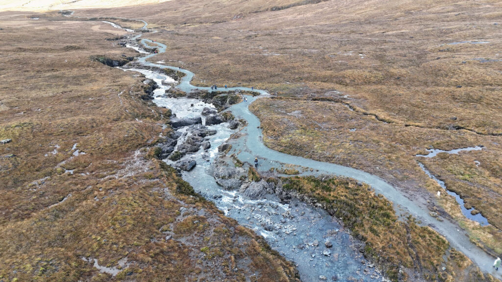 Vue aérienne d'un sentier sinueux longeant une rivière et des petites cascades rocheuses aux Fairy Pools, sur l'île de Skye en Écosse.