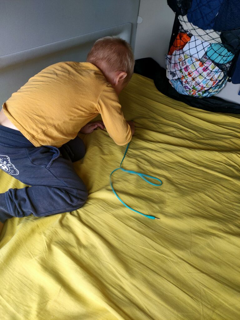 Un enfant joue sur le lit aménagé à l’intérieur du van, utilisé aussi comme espace de vie pendant la journée.